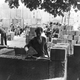 A worker builds the wall, watched by East German soldiers